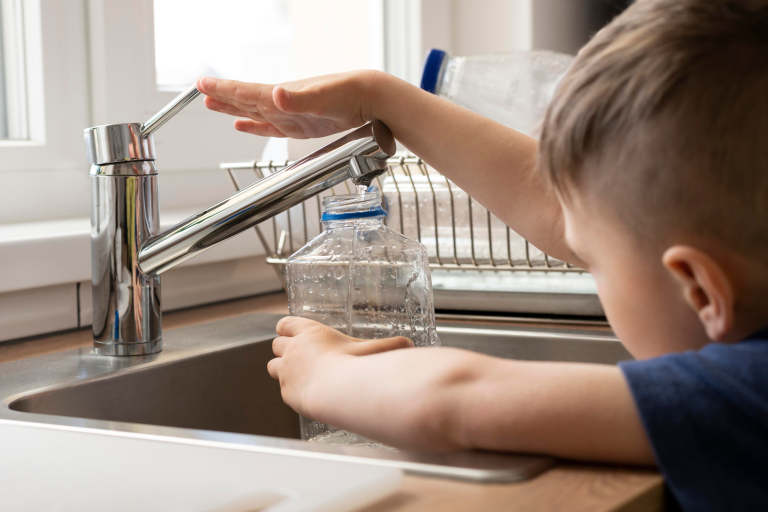 enfant qui remplit une bouteille d'eau